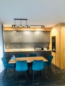 a kitchen with a wooden table and blue chairs at Solankowa Aleja Apartament Rodzinny in Inowrocław