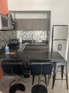 a kitchen with a black counter and some chairs at Cancun Plaza Condo Mexico in Cancún