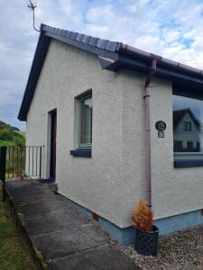 Cette petite maison blanche dispose d'une fenêtre et d'une terrasse couverte. dans l'établissement Kings Reach - Dunadd Cottage, à Kilmichael Glassary
