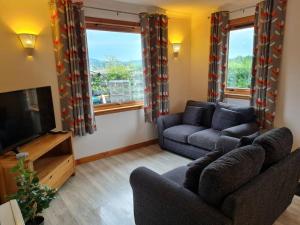 sala de estar con sofá y TV en Kings Reach - Dunadd Cottage en Kilmichael Glassary