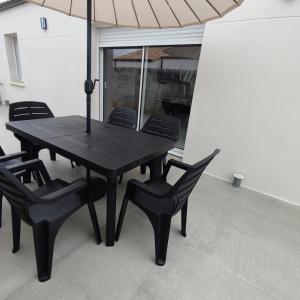 a black table and chairs with an umbrella at Maison neuve à 13 min des Sables in Talmont