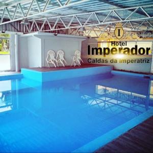 a swimming pool with two white chairs on top of it at Hotel Imperador Caldas in Santo Amaro da Imperatriz