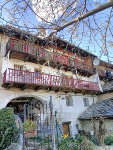 een oud huis met rode balkons op een gebouw bij Maison du Mont in Aosta