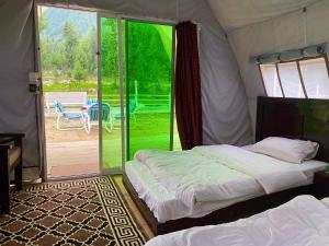 a bedroom with two beds in a tent with a patio at Valhalla Resort Kumrat in Tāl