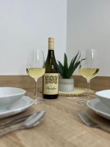 a bottle of white wine and two glasses on a table at In Dream Apartman in Inđija