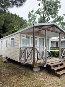 een stacaravan met een veranda en een terras bij Mobile home camping in Le Grau-du-Roi
