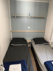 two beds in a small room with shelves at Mobile home camping in Le Grau-du-Roi