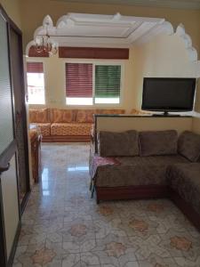 ein Wohnzimmer mit einem Sofa und einem Flachbild-TV in der Unterkunft Appart centre in Larache