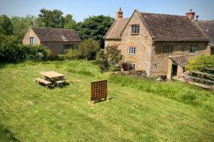 einen Picknicktisch im Hof eines alten Hauses in der Unterkunft Whichford Mill-large Cotswold Home in Shipston on Stour