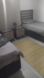 1 dormitorio con 2 camas, escritorio y alfombra en Wanderlust Hostel, en Bergville
