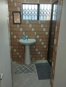 a bathroom with a sink and a brick wall at Wanderlust Hostel in Bergville