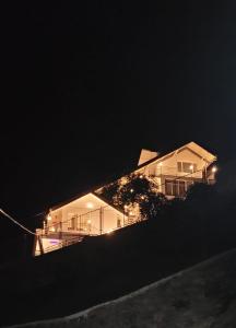 a house on a hill at night with lights at Castra villas in Vandiperiyār