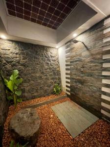 a bathroom with a stone wall and a shower at Castra villas in Vandiperiyār