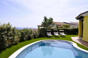 a swimming pool in a yard with two lawn chairs at Villa Nadia con piscina privata Budoni in Tanaunella