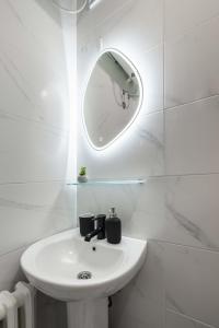 uma casa de banho branca com um lavatório e um espelho em Old Town Rooms em Novi Sad