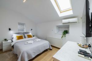 a white bedroom with a bed and a window at Old Town Rooms in Novi Sad