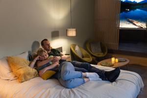 un hombre y una mujer acostados en una cama en Plaisances, les plaisirs du bord de Meuse - Chambre d'hôtes avec baignoire spa, en Profondeville