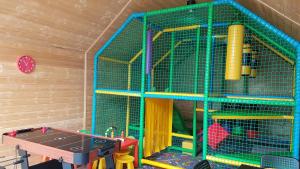 a play room with a cage and a table at Osada Wypoczynku Jantar Resort&Spa - Luksusowe Domki z Basenem, Sauną i Jacuzzi in Jantar