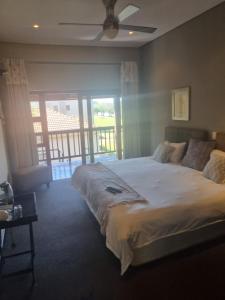 a bedroom with a large bed with a ceiling fan at Emufuleni river logde in Vanderbijlpark