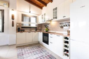 a kitchen with white cabinets and a rug at The Serenity Stone Lodge in Kavala