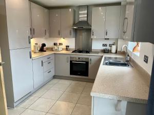a kitchen with white cabinets and a sink at 3 Bed Stylish house with parking close the Etihad in Manchester