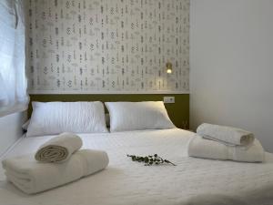 Una cama blanca con toallas y almohadas. en VIDAL APARTAMENTOS con parking privado. en Carmona