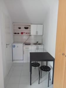 een kleine keuken met een zwarte tafel en twee krukken bij Apartmani Lovcen in Prolom