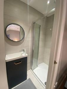 La salle de bains est pourvue d'une douche, d'un lavabo et d'un miroir. dans l'établissement Baker House (Ormeau Road) 4Bed, à Belfast