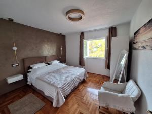a bedroom with a bed and a chair and a window at Apartman K. & M. KOLUMBIĆ in Sveta Nedelja