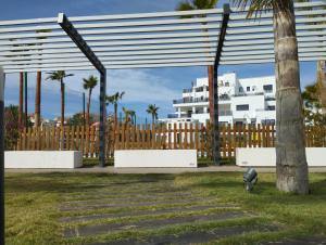 un parc avec des palmiers et un bâtiment blanc dans l'établissement Lola Home Aguacate Beach, à Motril