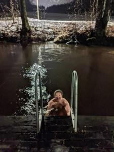 un homme qui saute d'un quai dans une masse d'eau dans l'établissement Troll House Eco-Cottage, Nuuksio for Nature lovers, Petfriendly, à Espoo