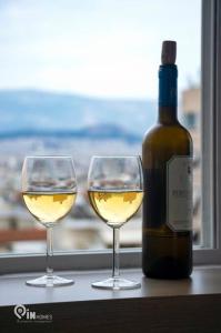 Dois copos de vinho branco ao lado de uma garrafa de vinho em Athenian Sky View - next to Metro em Atenas