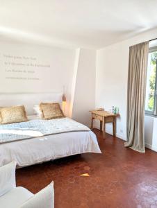 een witte slaapkamer met een bed en een tafel bij La Bâtisse en Blanc in Golfe-Juan