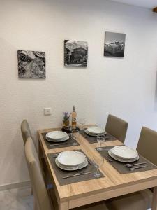 tavolo da pranzo con sedie e tavolo con piatti e bicchieri di Apartments Arcadia a Saas-Grund