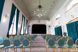 una habitación con sillas y un escenario en el fondo en Hotel Prácheň, en Horažďovice