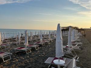 un gruppo di sedie e ombrelloni in spiaggia di [Chi Ama il Mare] Appartamento a Latina