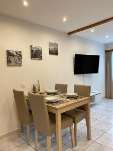 a dining room with a table with chairs and a television at Apartments Arcadia in Saas-Grund