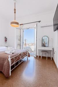 a bedroom with a bed and a desk and a television at Syros DouBleTS rooms in Ermoupoli