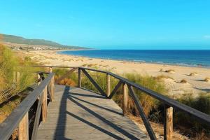 eine hölzerne Promenade, die zu einem Strand mit dem Meer führt in der Unterkunft Vacaciones en España in Isla Cristina