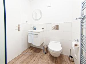a white bathroom with a toilet and a sink at Mein Strand Apartment in Scharbeutz