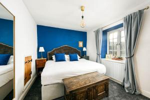 a bedroom with a large bed with blue walls at The Farmhouse with two hot tubs in Siston