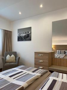 1 dormitorio con cama, silla y espejo en Apartments Arcadia, en Saas-Grund
