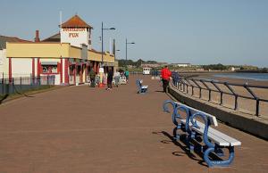 a bench on a boardwalk next to the water at Beach Walk in Berwick-Upon-Tweed