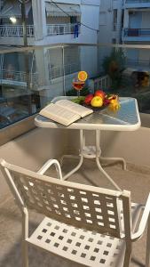 a table and a chair with a book and fruit on it at Plagia Relax Hotel in Nea Plagia