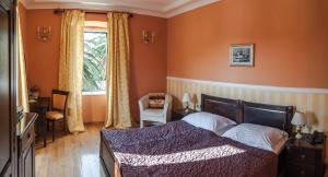 1 dormitorio con 1 cama con paredes de color naranja y ventana en Boutique Hotel Villa Pattiera, en Cavtat