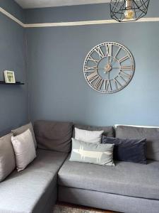 a living room with a couch with a clock on the wall at Cosy 2 bed flat in Crickhowell in Crickhowell