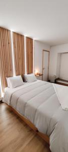 Cette chambre comprend un grand lit blanc et du parquet. dans l'établissement Santi e Benny Apartment, à Ponta Delgada