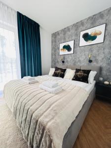 een slaapkamer met een groot bed met een grijze muur bij Apartament Zielony Pobierowo Baltic Apartments in Pobierowo