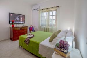 ein Schlafzimmer mit einem Bett mit einer grünen Decke und einem TV in der Unterkunft Villa La Natura x9 Whole villa with private parking in Sorrent