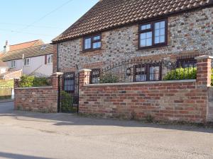 a brick house with a fence in front of it at Whitestones Cottage in Caister-on-Sea